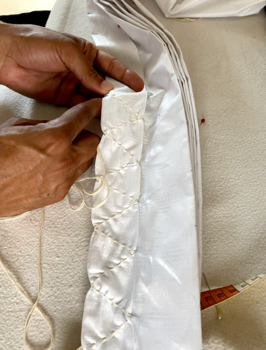 A person sewing a white fabric Description automatically generated